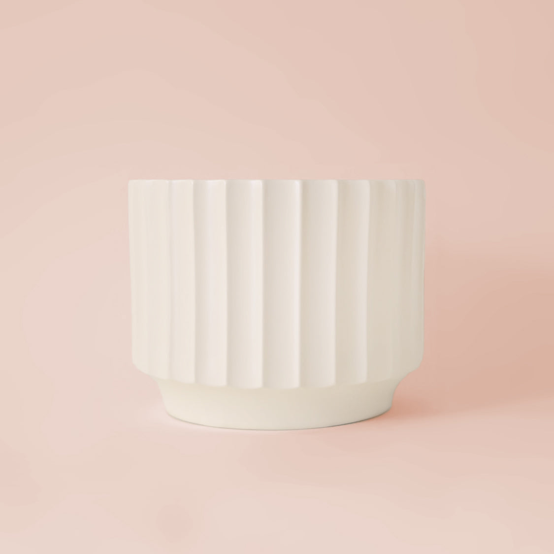 A black fluted ceramic planter with a plant inside sold separately.
