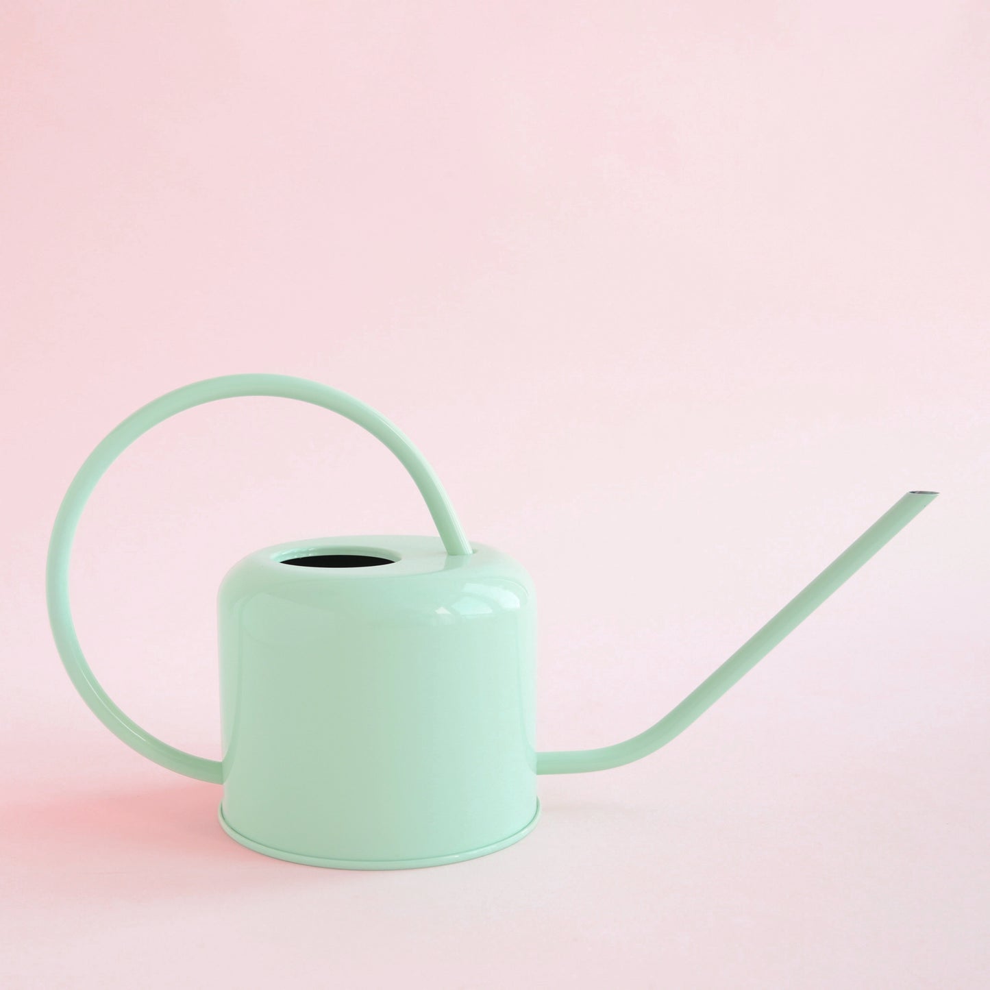 On a pink background is a light blue watering can with a long spout and a rounded handle.