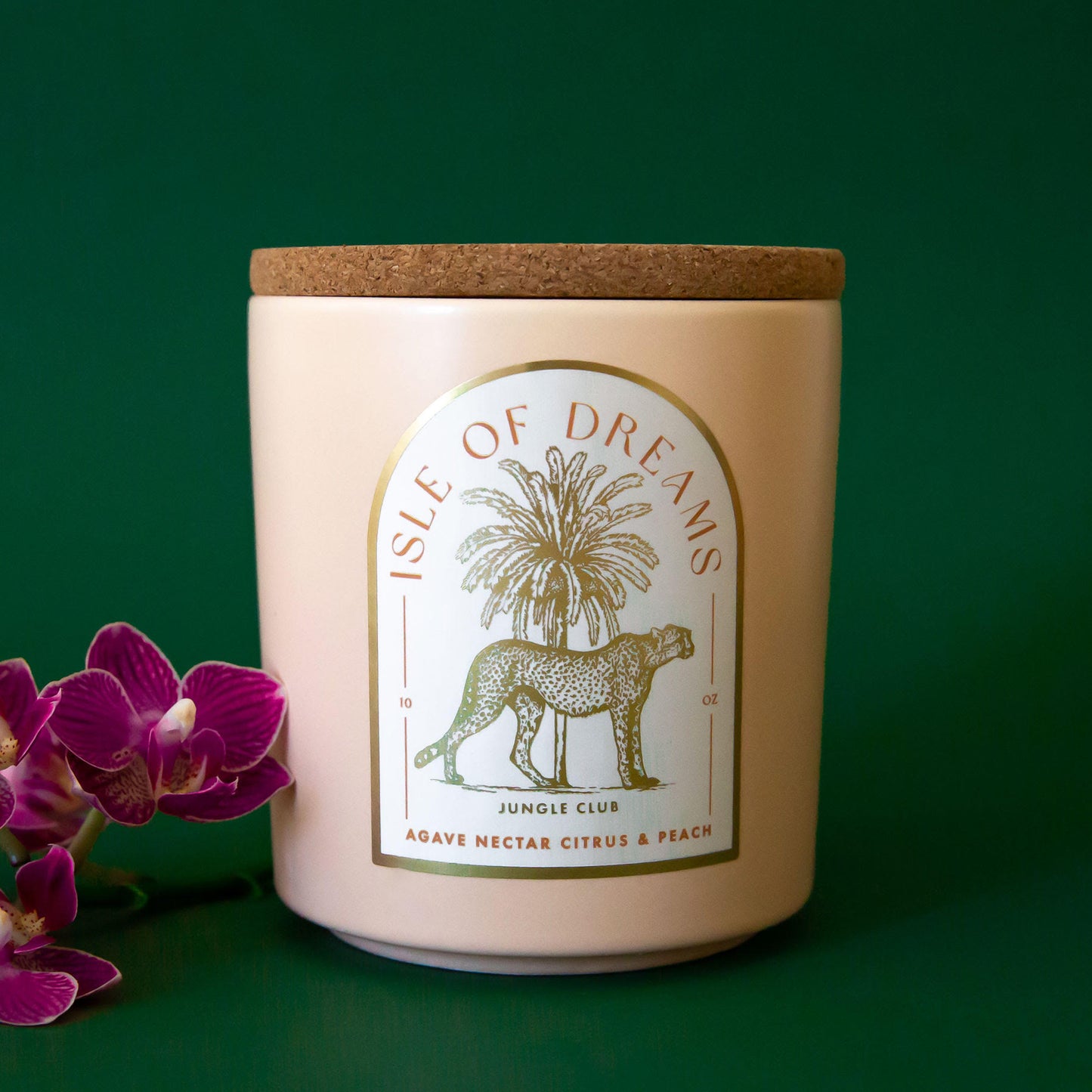 A neutral candle with an arched label with a cheetah and palm tree graphic and text that reads, 'Isle of Dreams'.