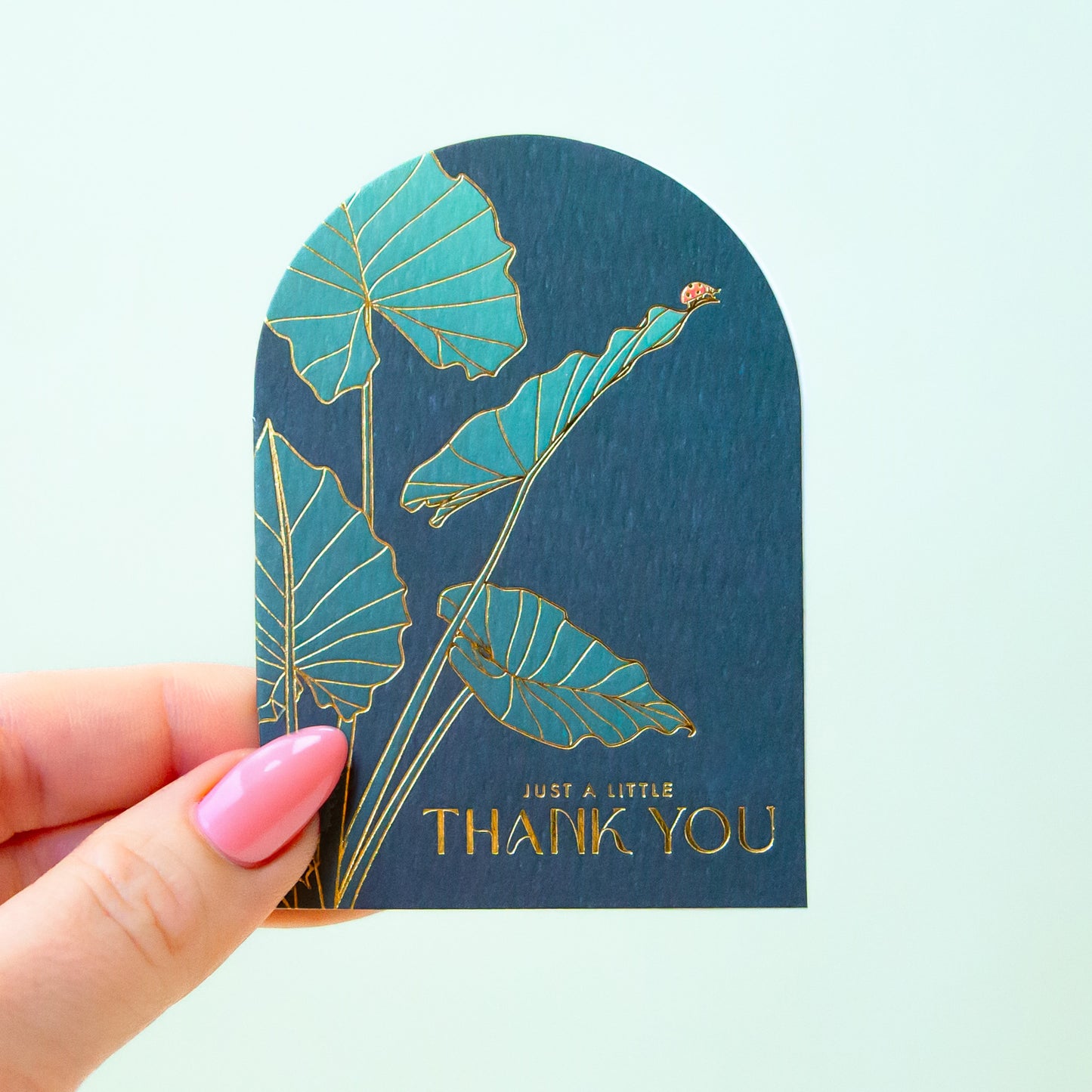 An arched dark teal card with gold foiled text that reads, 'Just a Little Thank You'.