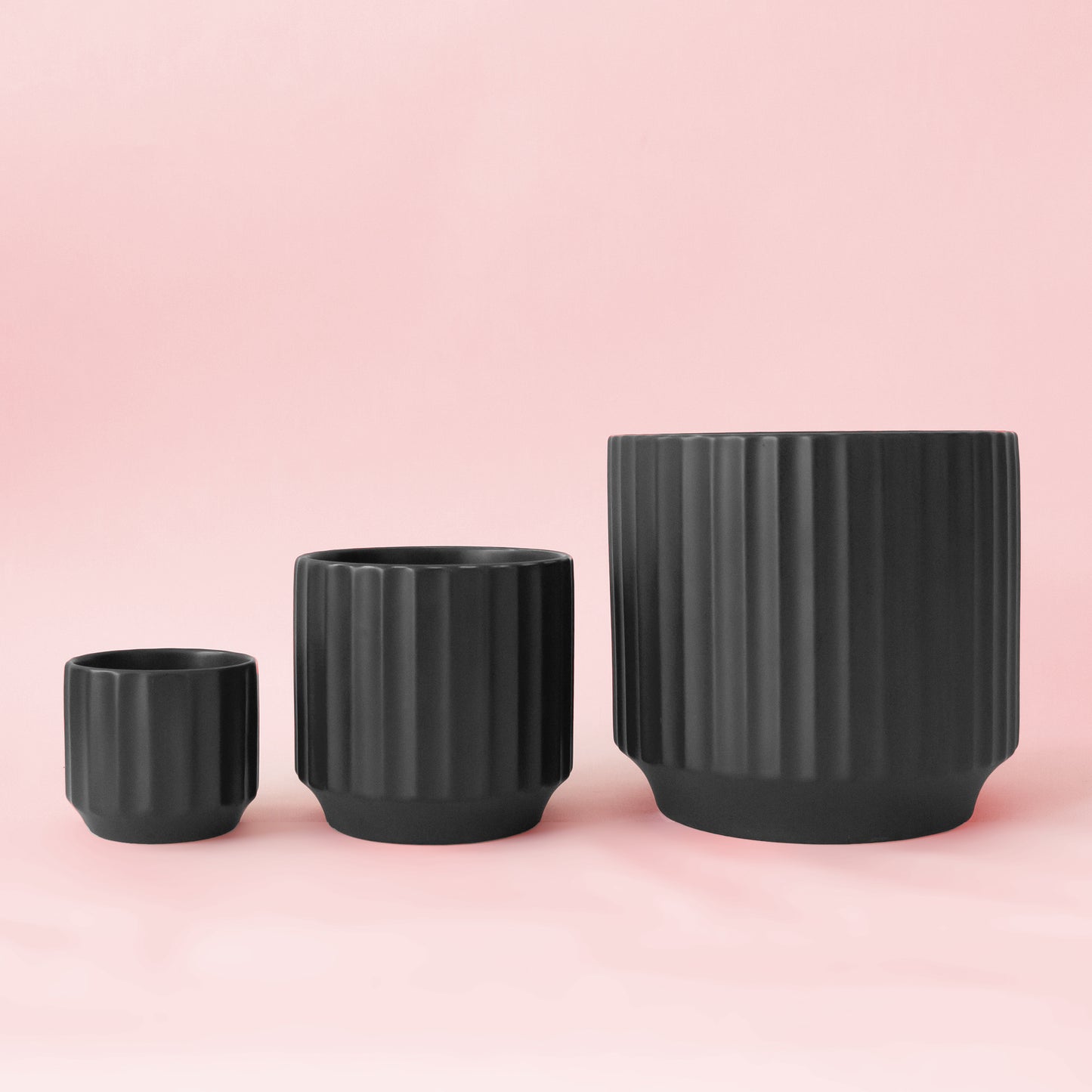 A black fluted ceramic planter with a plant inside sold separately.