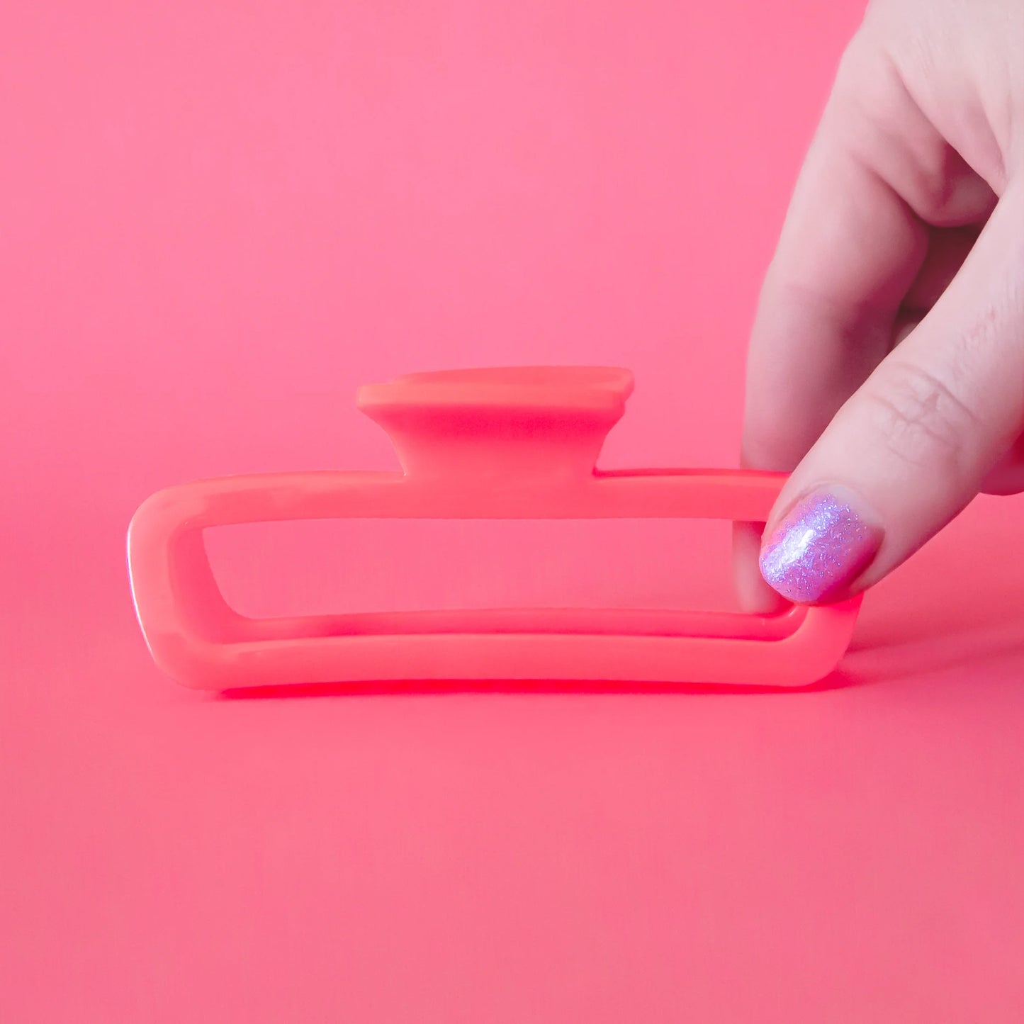 A pink rectangle hair clip with rounded edges.
