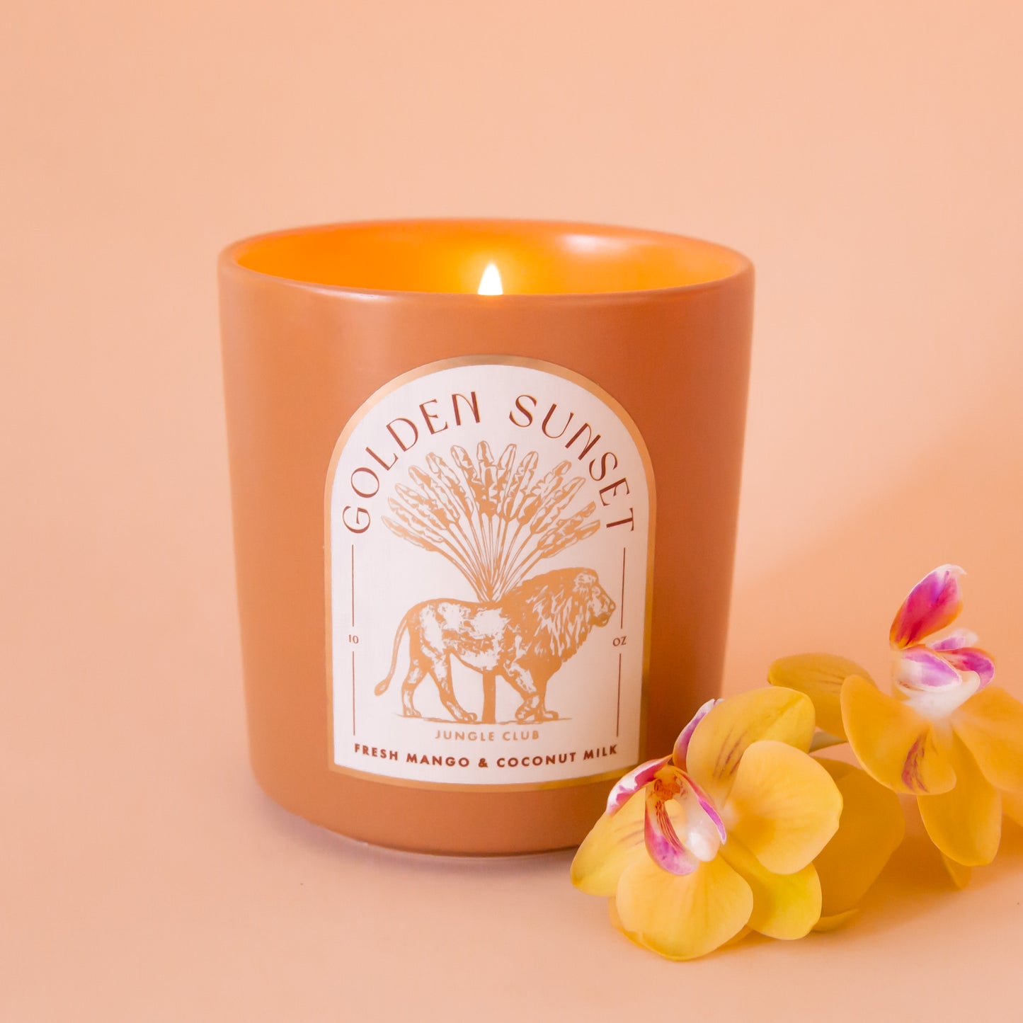 An orange candle with an arched label with a lion graphic and text above that reads, 'Golden Sunset'.
