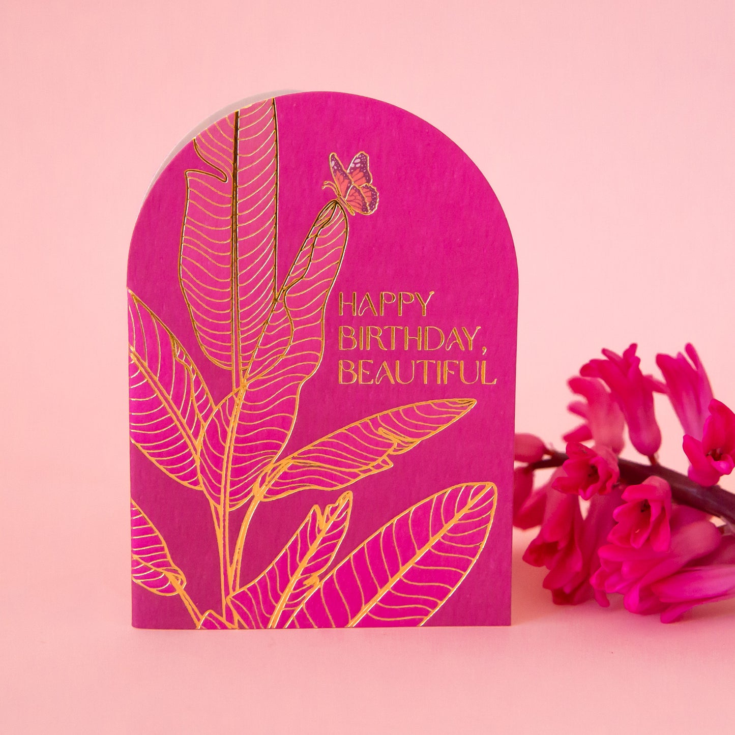 A hot pink arched card with gold foiled text that reads, 'Happy Birthday Beautiful'