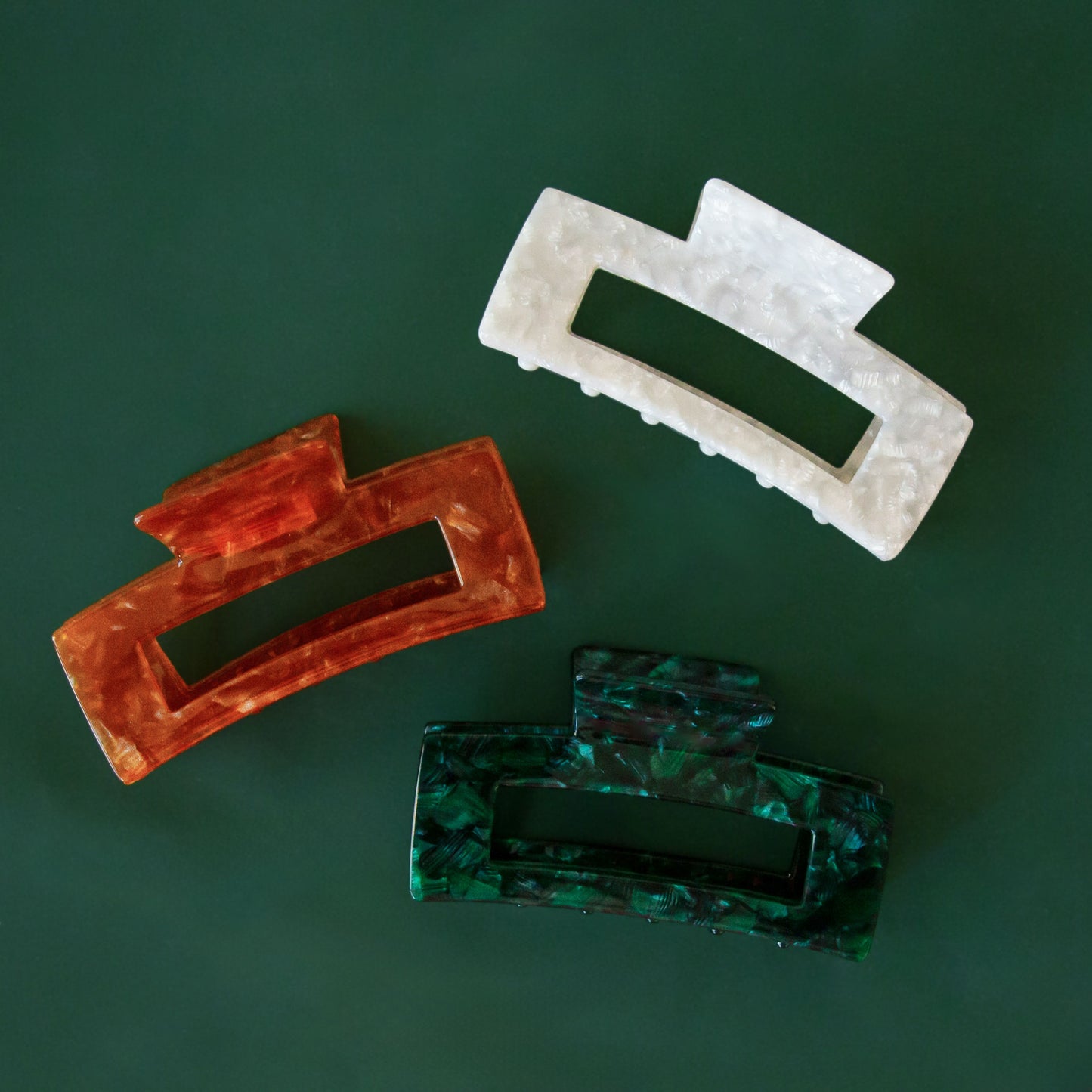 A photo of three different colors of the paradise hair claw clips.