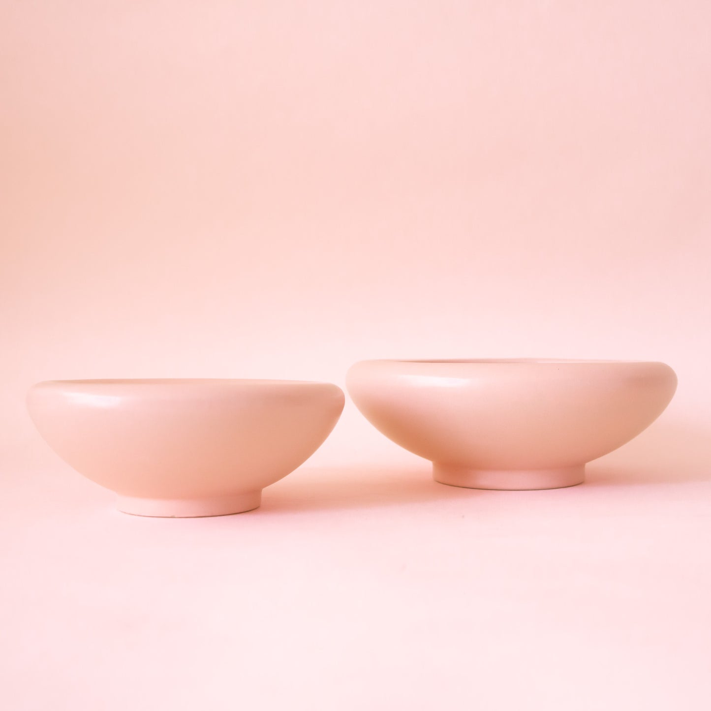 A light pink ceramic low bowl planter with a rounded edge.