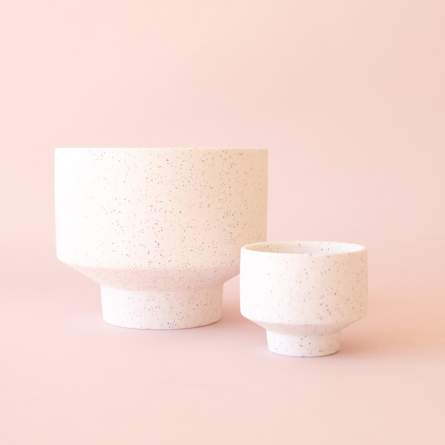A speckled footed ceramic planter in a neutral shade.