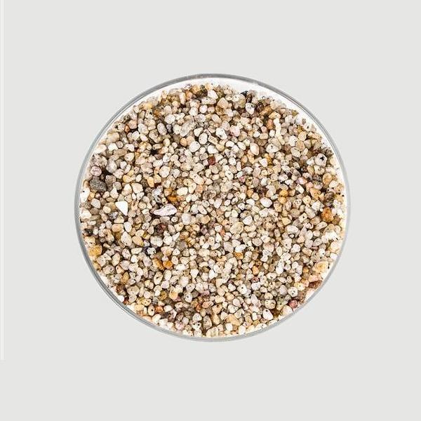 On a light grey background is a bowl of white and tan terrarium pebbles.