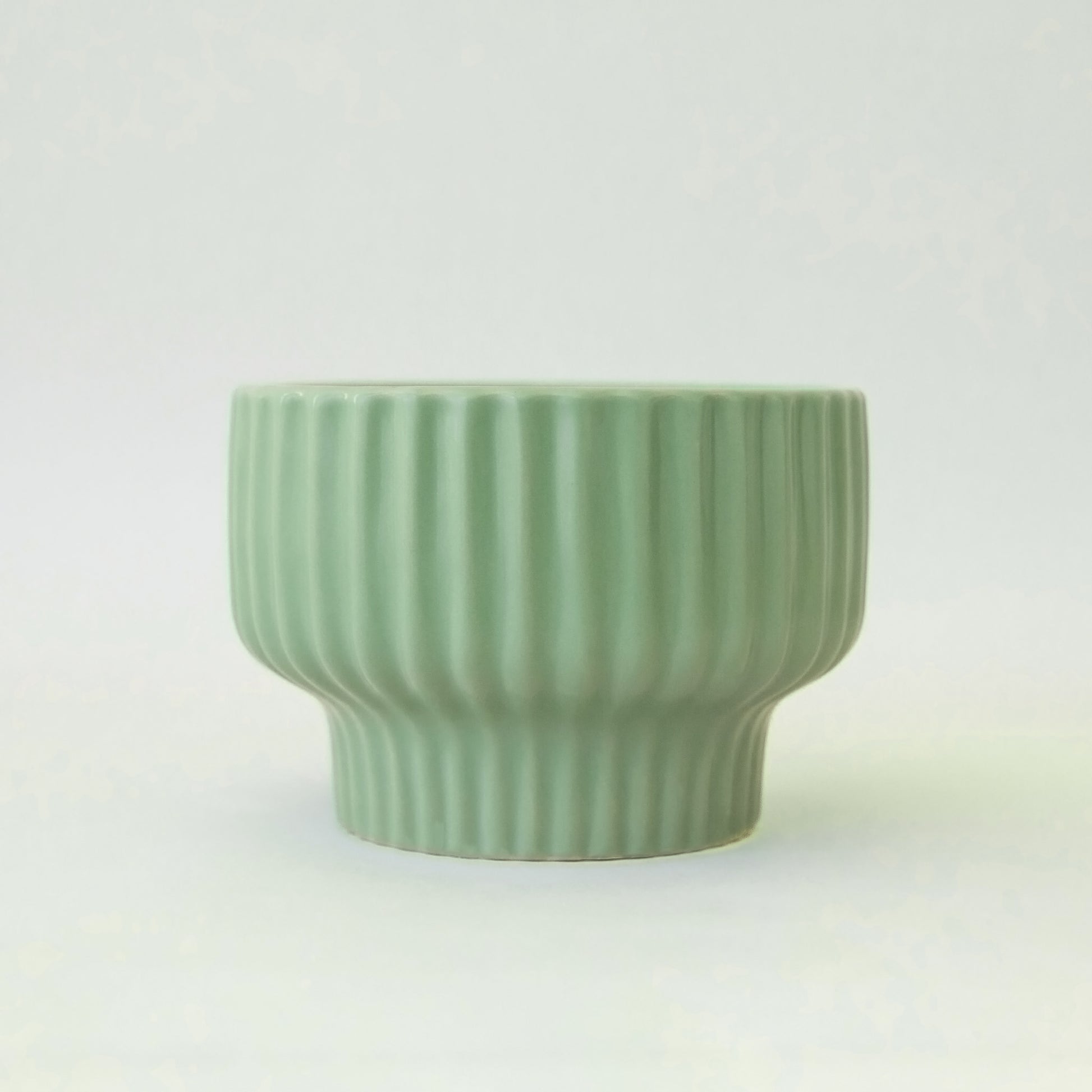 A jade green pedestal pot with a ribbed texture. 